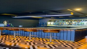 Un espace bar avec un sol à motifs, des tabourets de bar et un comptoir où sont exposées différentes bouteilles.