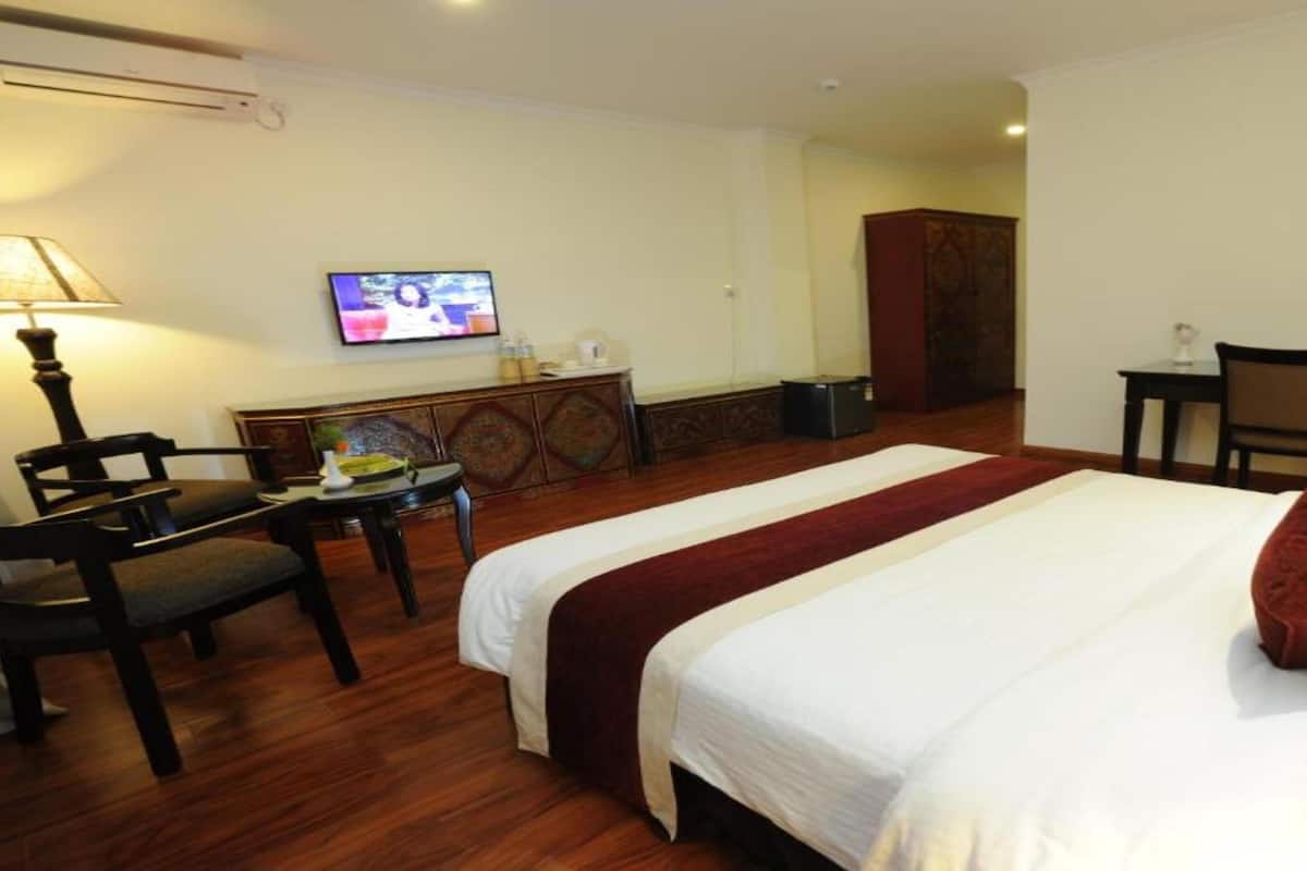 A hotel room with a bed, a desk, a chair, a television, and a wardrobe.