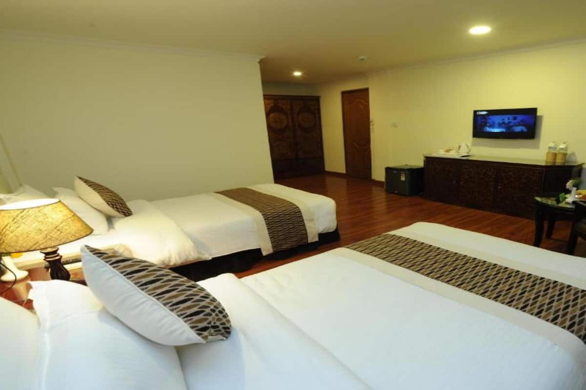 A hotel room with two beds, a desk, a chair, a TV, and a minibar.