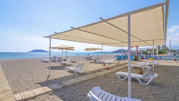 Playa privada, playa de arena negra, camastros y sombrillas