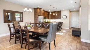 A modern kitchen with dark wooden cabinets, a central island, and pendant lighting.