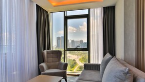 A modern hotel room with a large window, a sofa, a chair, and a small table. - Batumi View Luxury  (Batumi)