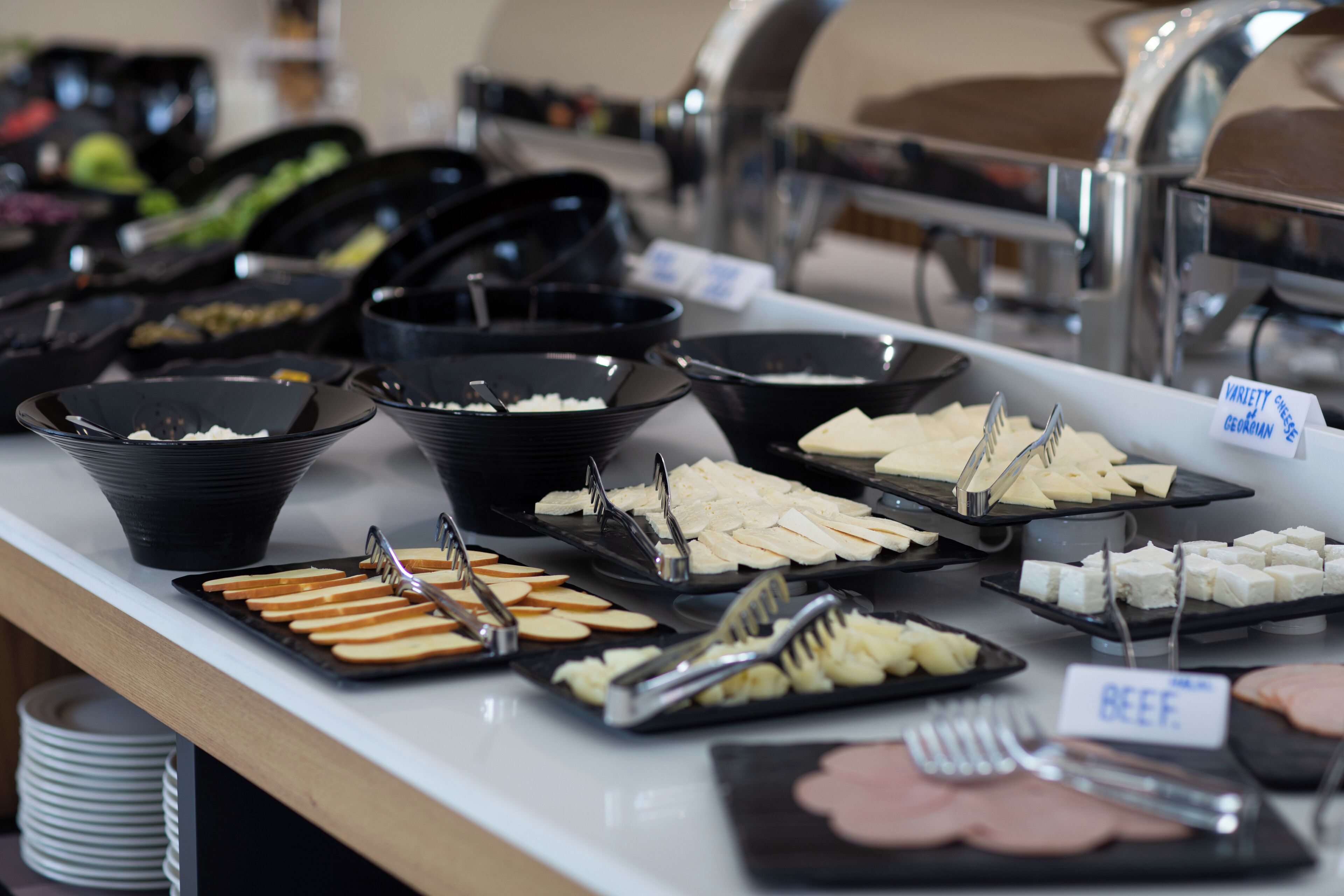 A buffet with various food items including cheese, bread, and meat.