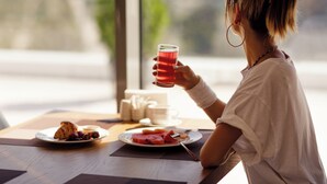 A person sitting at a table with a plate of food, a glass of red drink, and a cup. - Batumi View Luxury  (Batumi)