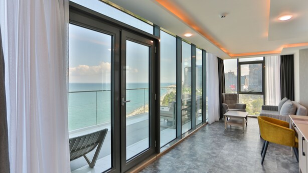 A modern living room with large glass doors leading to a balcony, a sofa, a yellow chair, and a coffee table. - Batumi View Luxury  (Batumi)