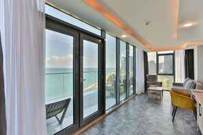Una sala de estar moderna con puertas de cristal grandes que dan a un balcón, un sofá, un sillón amarillo y una mesa de centro.
