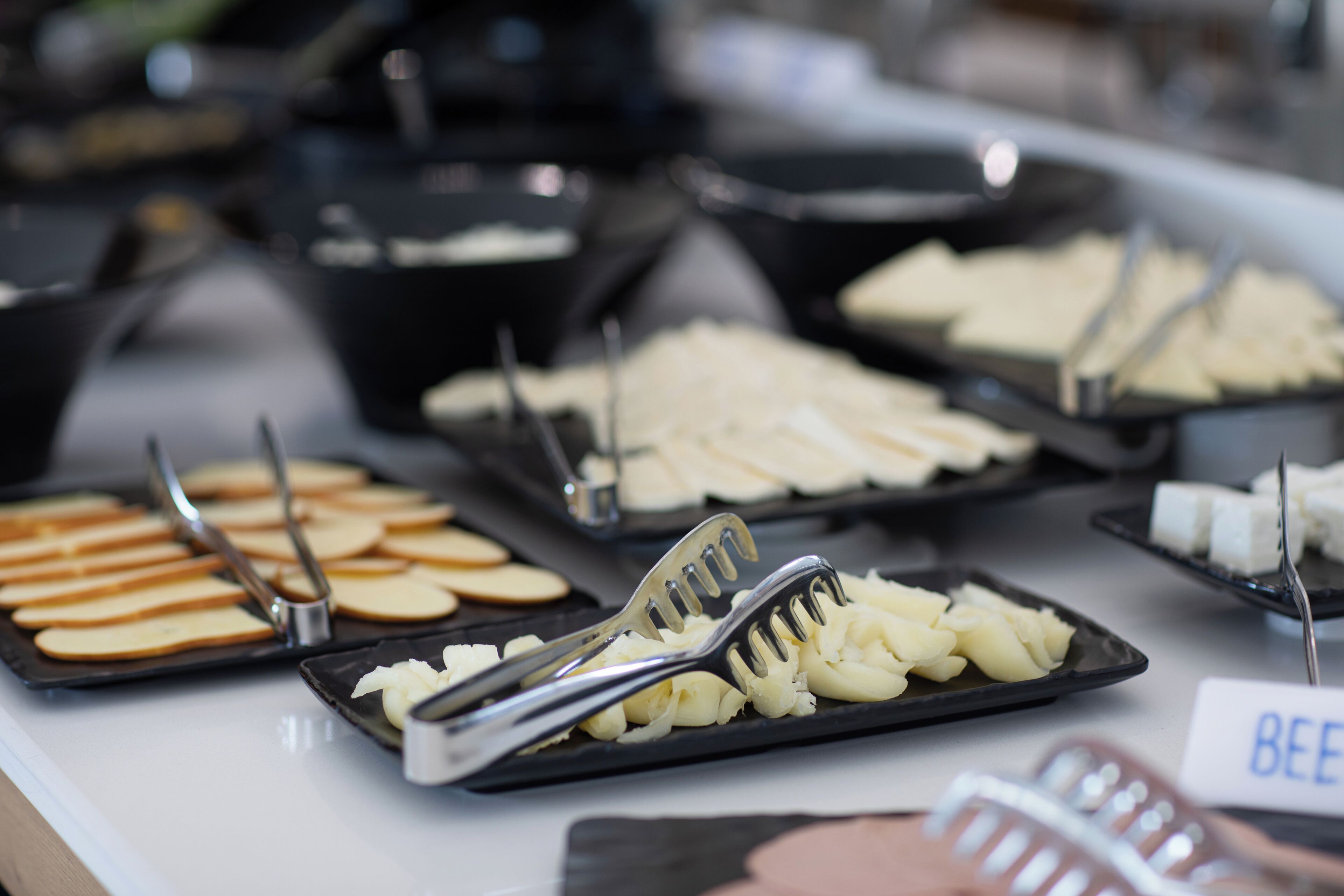 A buffet with various food items including sliced apples, cheese, and a sign labeled "BEEF".
