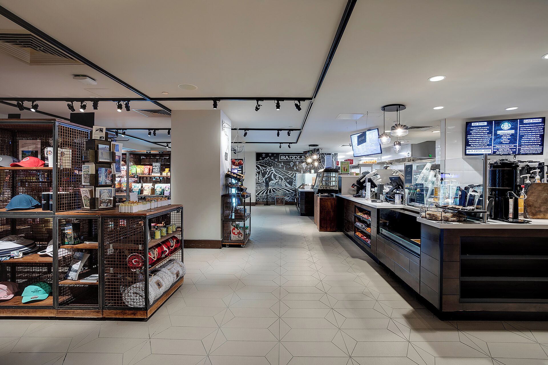 L'intérieur d'un café moderne, avec un comptoir, un espace salon et une variété de produits alimentaires et de boissons exposés.