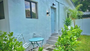 Una casa de color azul claro, con una puerta azul y un pequeño patio con una mesa y sillas.