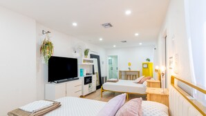 Una habitación de hotel moderna con una cama, un escritorio, un televisor y un baño visible al fondo.