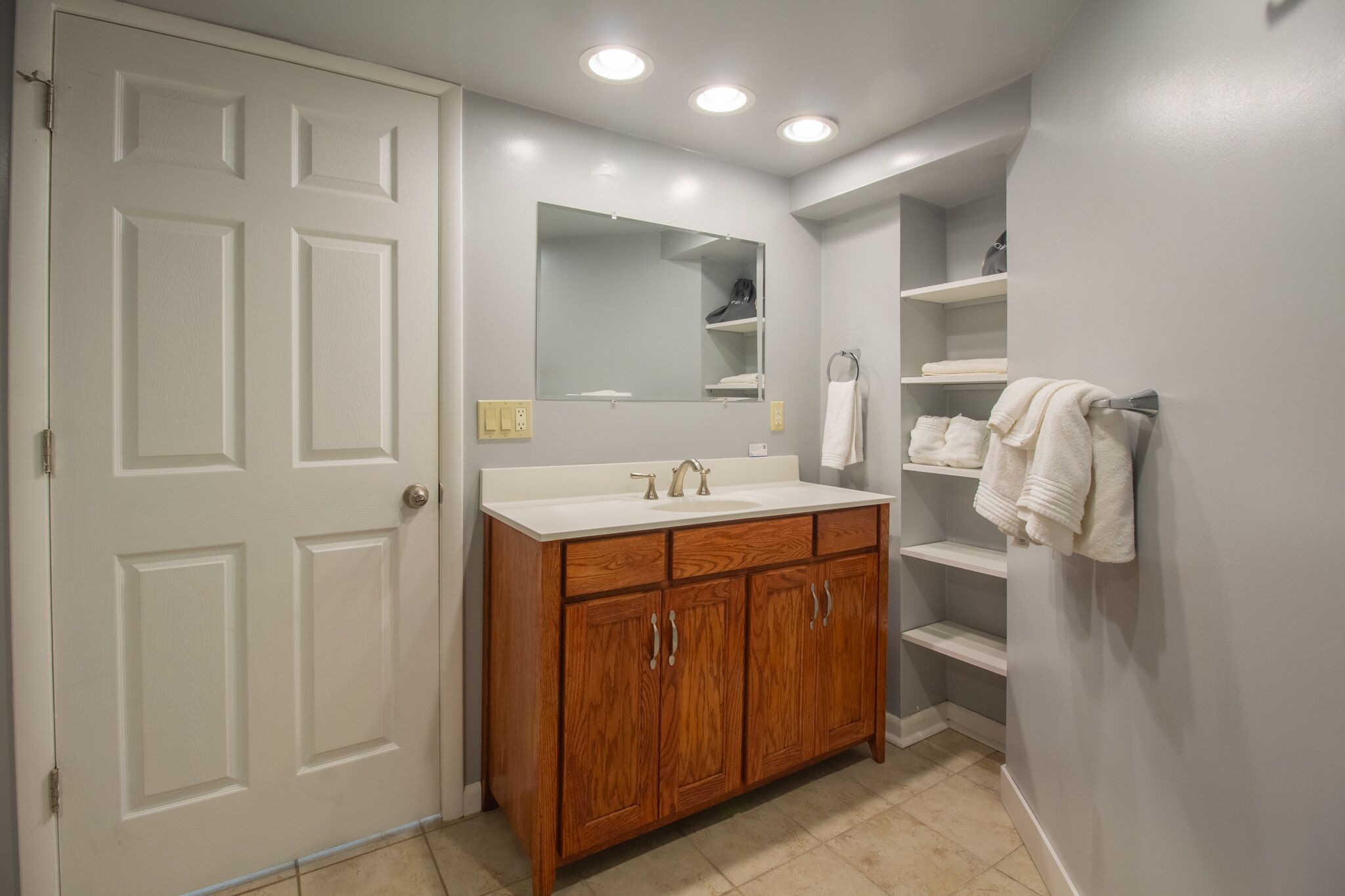 A bathroom with a wooden vanity, a mirror, and a towel rack.