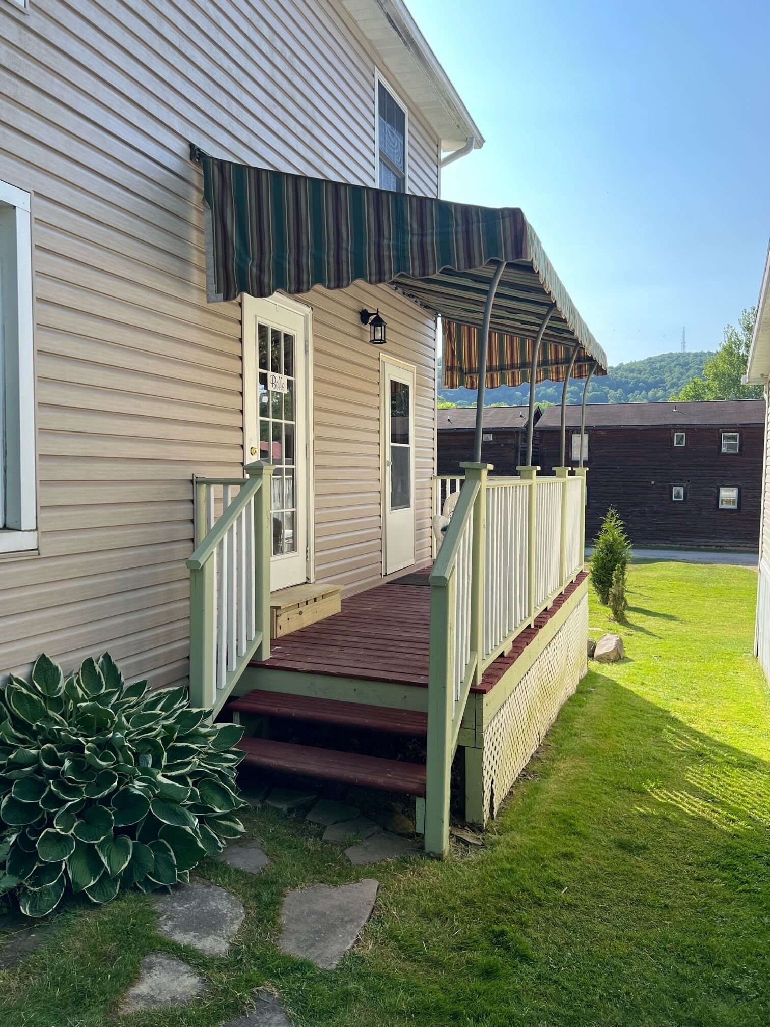 A house with a wooden deck, a covered porch, and a small garden area with stepping stones.