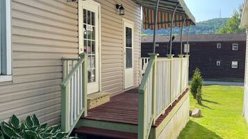 A house with a wooden deck, a covered porch, and a small garden area with stepping stones.