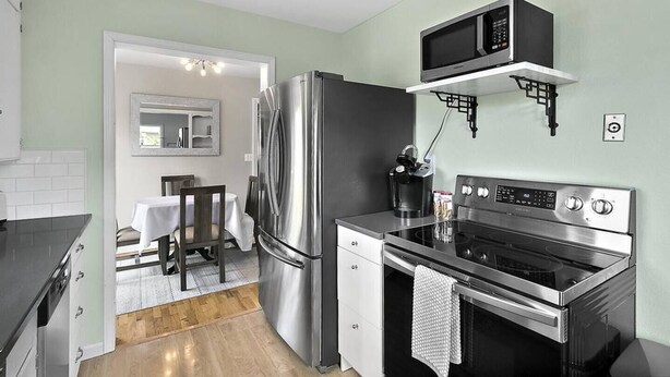 Une cuisine compacte équipée d’un réfrigérateur, d’un four à micro-ondes, d’une cuisinière et d’un petit coin repas avec une table et des chaises.