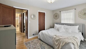 Een slaapkamer met een bed, een kledingkast, een spiegel en een deur naar een badkamer.