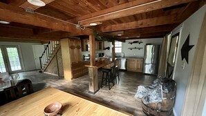 Una cocina amplia con armarios de madera, una isla central y un comedor con mesa y sillas de madera.