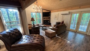 Amplio salón con un sillón de cuero grande, un sofá y una chimenea.