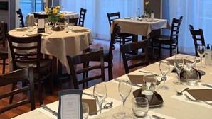 Een restaurant met ronde tafels, klaar voor het diner, met menu's, bestek en glazen.