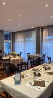 Un restaurante con mesas redondas dispuestas para comer, con menús, cubiertos y vasos.