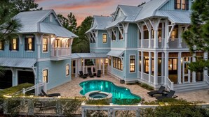 Un'ampia casa blu chiaro con piscina, diversi balconi e zone relax all'aperto.