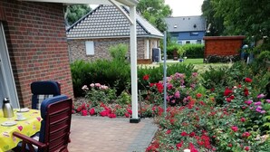 A patio with a brick floor, a table with a yellow tablecloth, and red chairs. - 2 bedroom private vacation home in wurster nordseekã¼ste (Wurster Nordseeküste)