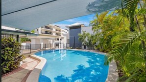 Una piscina rodeada de exuberante vegetación y edificios modernos.