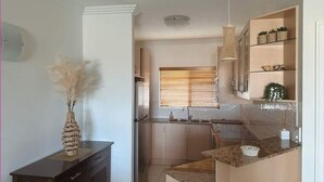 Una cocina compacta con una isla central, un armario de madera oscura y una lámpara colgante.