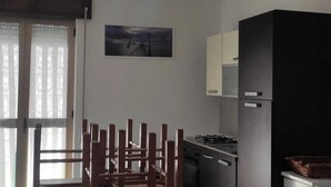 Une cuisine moderne équipée d’une cuisinière à gaz, de meubles noirs et d’un coin repas avec une table et des chaises en bois.