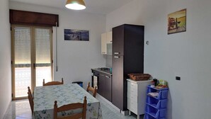 Une cuisine compacte comprenant une table et des chaises, un réfrigérateur et une cuisinière.