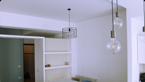 Un comedor con una mesa blanca, sillas y una lámpara colgante.