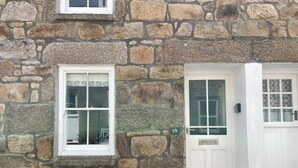 A stone building with two windows and a door, each with white frames and glass panes. - Howards Way - a cottage that sleeps 5 guests in 2 bedrooms (St Ives)