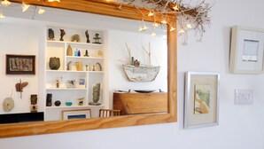 Una habitación con un aparador de madera, estantes con diversos objetos decorativos, un cuadro enmarcado y un modelo de barco.