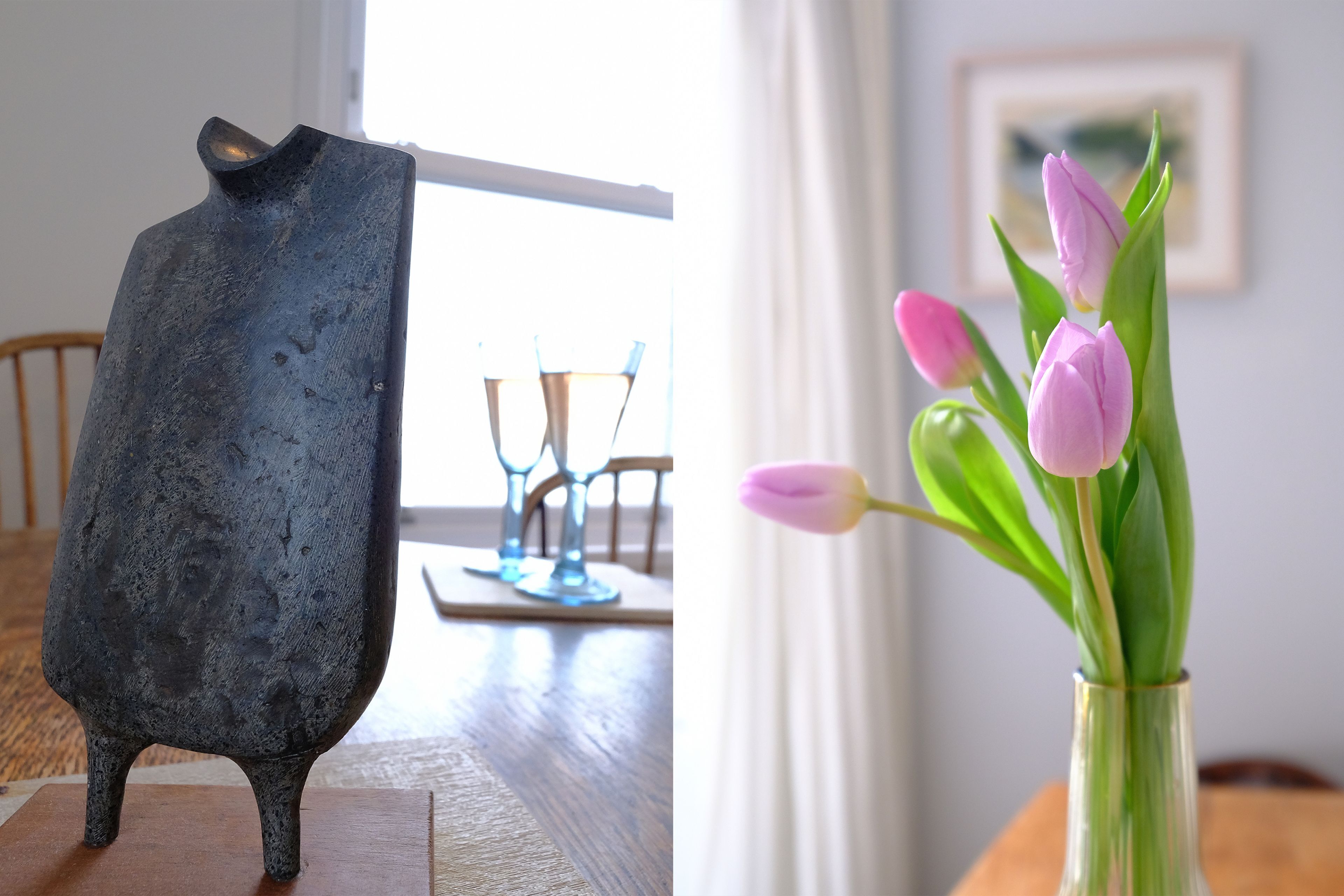 A rustic metal sculpture on a wooden table, a vase with pink tulips, and a dining area with chairs and a table.