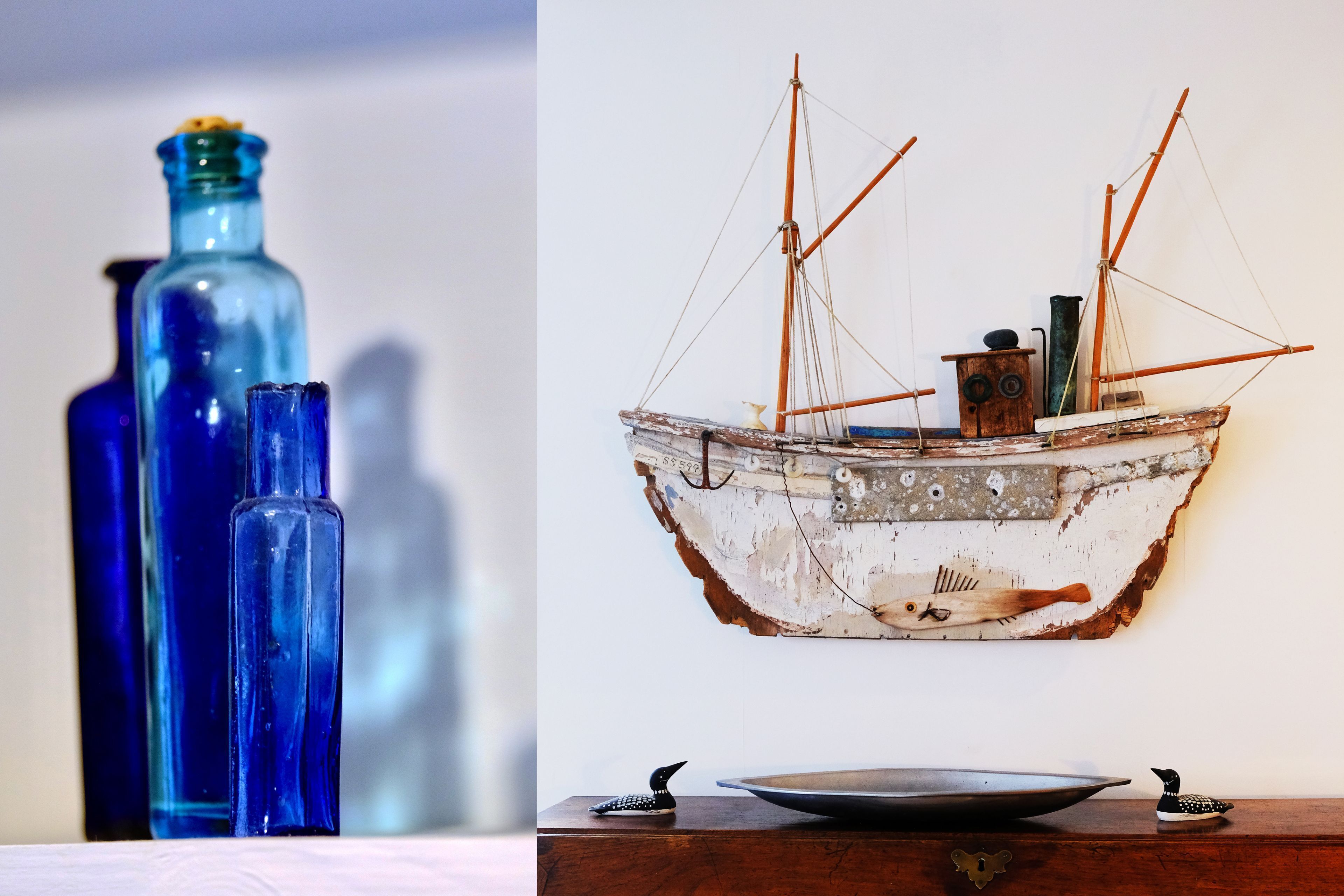 A ship model and three blue bottles on a table.