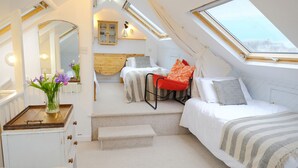 Un dormitorio ático acogedor con tragaluces, un cabecero de madera y un pequeño rincón de descanso.