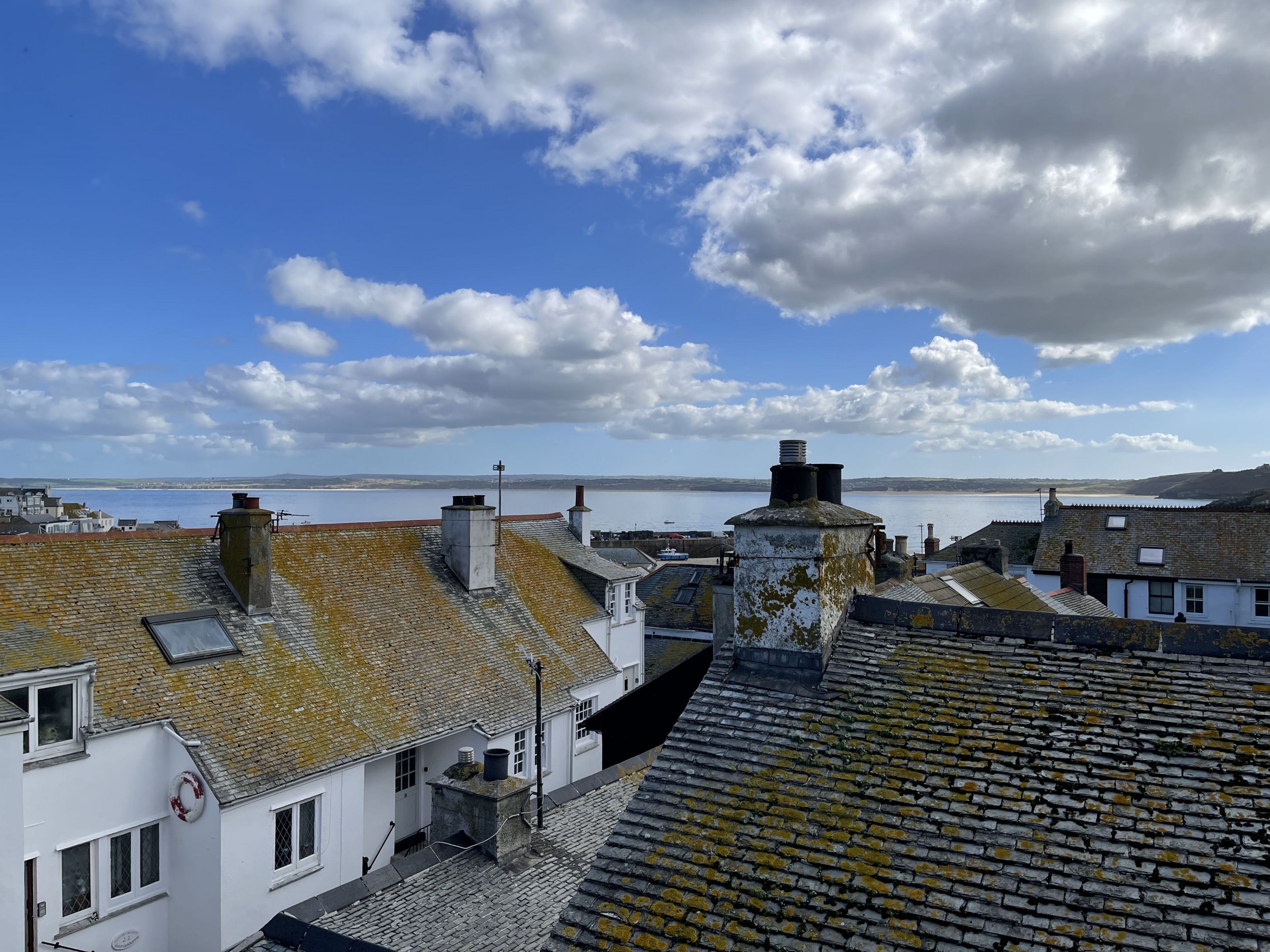 Uma vila costeira com edifícios de pedra tradicional, céu limpo e vista para o mar.