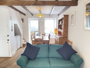Ein gemütliches Wohnzimmer mit einem grünen Sofa, einem Holzespeisetisch und einer Küche im Hintergrund.
