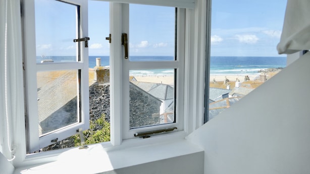 A view from a window overlooking a beach with buildings in the background. - Silver Seahorse - a cottage that sleeps 6 guests in 3 bedrooms (St Ives)