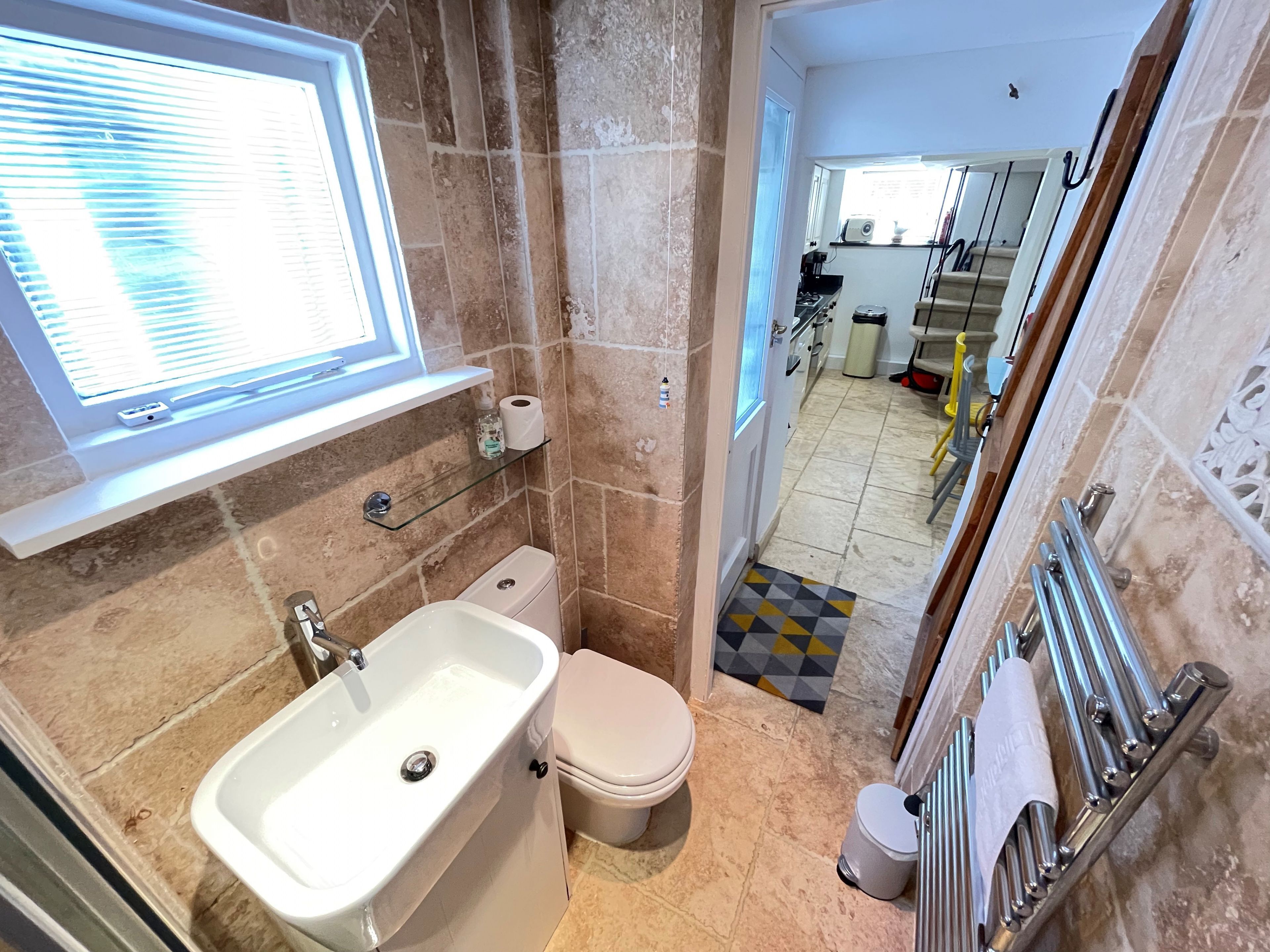 Een badkamer met een wastafel, toilet en een raam met zonwering.