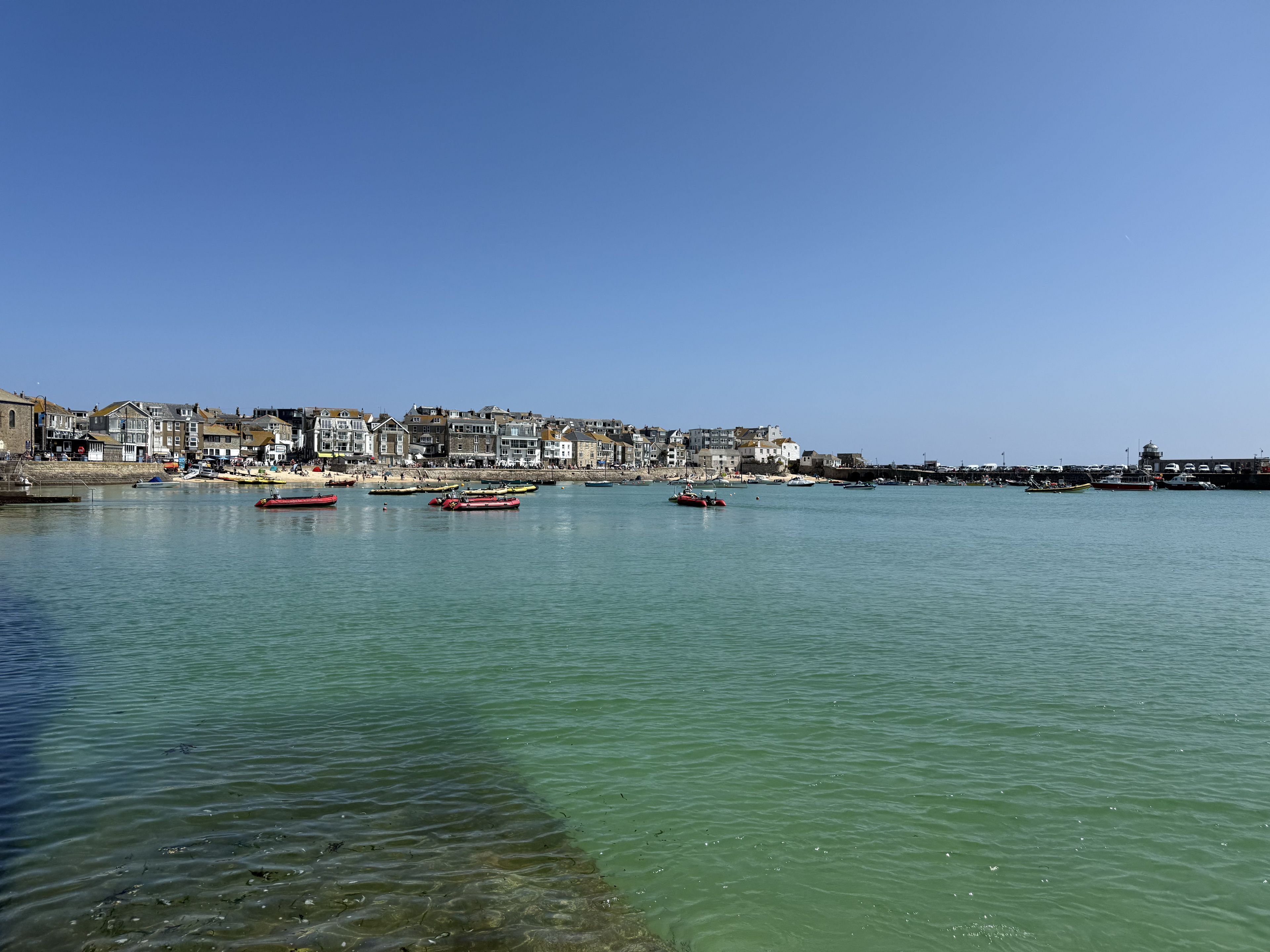 A coastal town with buildings along the waterfront, boats in the water, and a clear blue sky.