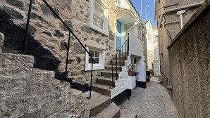 Un estrecho callejón con paredes de piedra y una escalera que conduce a una puerta blanca.