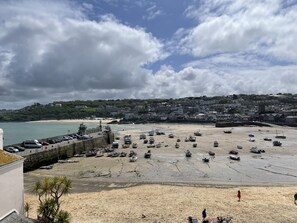 A beach with parked boats and a lighthouse in the background.
