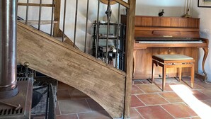 Eine Holztreppe mit Metallgeländer, ein Klavier und ein Spiegel an der Wand.