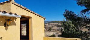 A yellow building with a tiled roof, a visible door, and a window overlooking a hilly landscape. - Le Cabanon des Vignes, an extraordinary place nestled among the vineyards (Vinsobres)