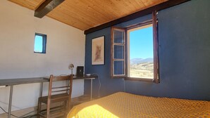 Ein Zimmer mit einem Bett, einem Schreibtisch, einem Stuhl, einem Fenster und einem kleinen Bild an der Wand.