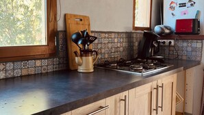 Eine Küche mit Gasherd, Holzschränken, Schneidebrett und Kaffeemaschine.