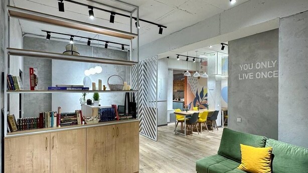 A modern living room with a green sofa, a wooden coffee table, and a striped bean bag. - izzzi hostel Bishkek (Bishkek)
