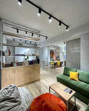 Ein modernes Wohnzimmer mit einem grünen Sofa, einem Holztisch und einem Sitzsack mit Streifen.