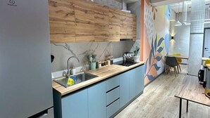 A modern kitchen with a wooden countertop, grey cabinets, and a built-in sink. - izzzi hostel Bishkek (Bishkek)