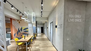 A modern interior with a long wooden table and yellow chairs, a kitchen area, and a motivational quote on the wall. - izzzi hostel Bishkek (Bishkek)